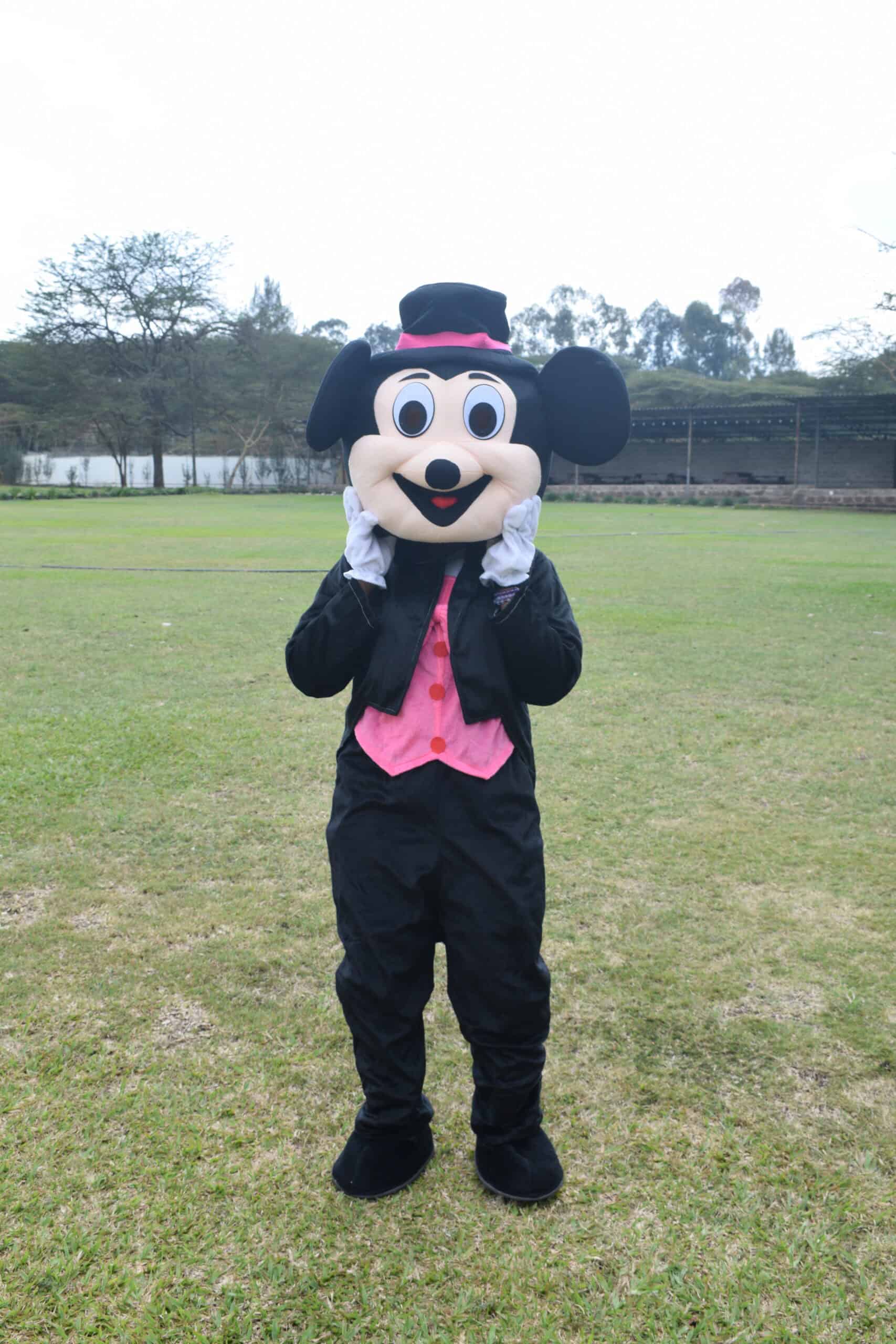 Pink Mickey is a Mascot With a bright pink outfit, big smile, and playful energy